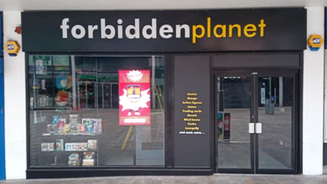 Bookshop storefront with "forbidden planet" sign, featuring colorful window displays and a large poster.