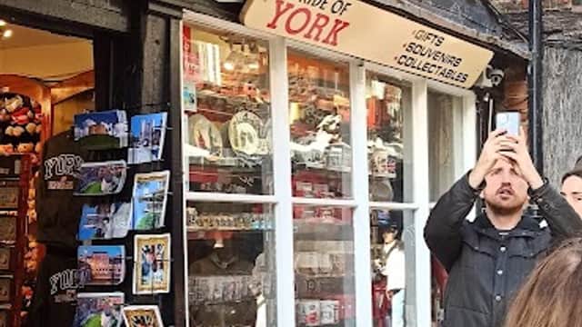 Charming gift shop with "Pride of York" sign, displaying souvenirs and postcards, surrounded by historic brick architecture.
