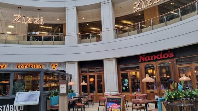 Shopping centre interior featuring Zizzi and Nando's restaurants, with seating and decorative lighting.