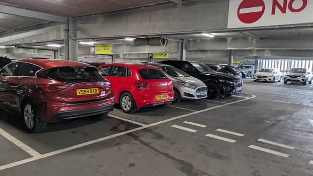 Multi-storey car park with parked vehicles, including red, silver, and black cars, and a "No Entry" sign visible.