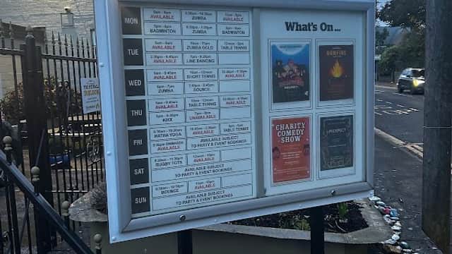 Signboard displaying event schedule and advertisements outside The Pie Hall in Denby Dale, Yorkshire, with decorative stones.