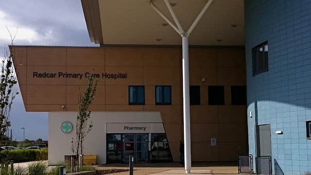 Redcar Primary Care Hospital entrance with modern architecture, large overhang, and pharmacy sign.