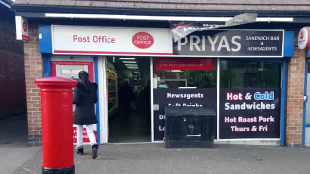 Post Office storefront with red post box, sandwich bar sign, and a customer entering the shop.