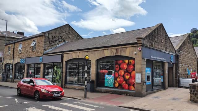 Co-op Food storefront in Hebden Bridge, featuring colorful apple display and a red car parked nearby.