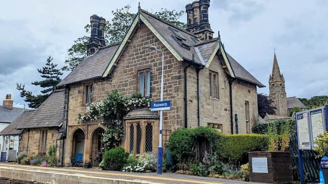 Historic stone building with a slate roof, surrounded by greenery, located at the Ruswarp train station.