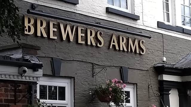 Signage for "Brewers Arms" bar, featuring flowers in hanging baskets and a welcoming entrance in East Cowick, Yorkshire.