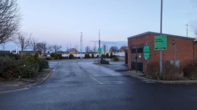 Public parking area in Thornaby, Yorkshire, featuring a brick building, signage, and surrounding trees.