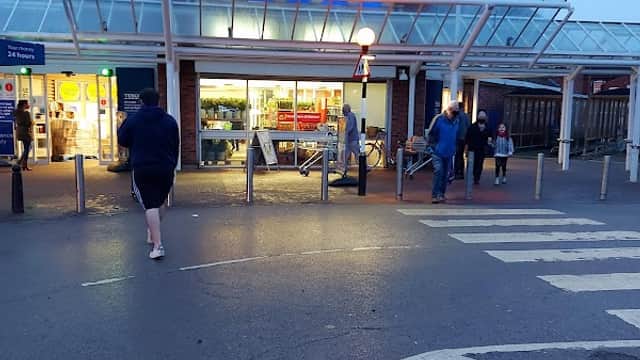 Tesco Superstore entrance with shoppers, illuminated sign, and a cloudy evening sky in Goole, Yorkshire.