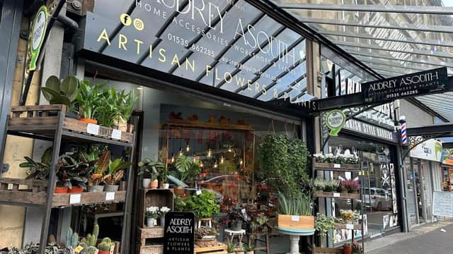 Floral shop entrance with diverse plants, flowers, and decorative items, featuring a sign for "Audrey Asquith".