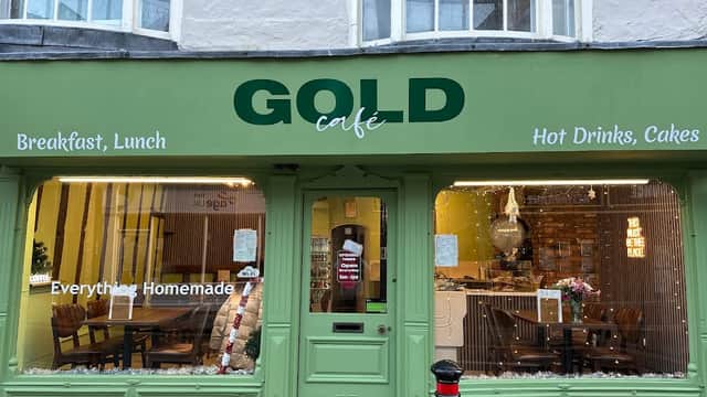 Green storefront of GOLD Café in York, featuring signs for breakfast, lunch, and homemade cakes. Warm, inviting atmosphere.