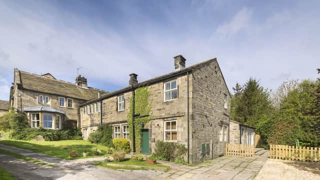Stone-built hotel with ivy-covered walls, surrounded by greenery and a gravel path leading to a wooden fence.