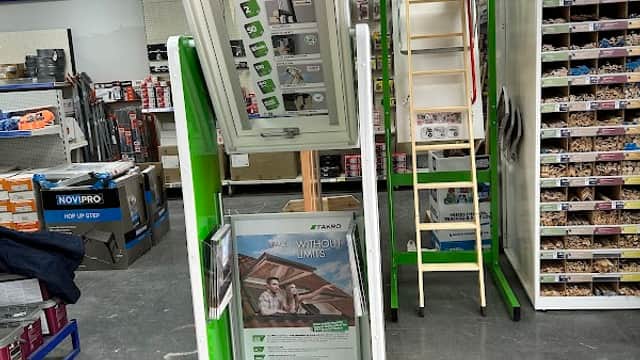 Display stand featuring FAKRO products, surrounded by shelves of ironmongery supplies in a retail setting.