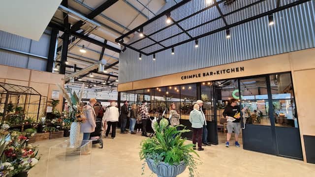 Interior of Weetons Leeds Road, featuring a bar-kitchen area, plants, and shoppers browsing in a spacious, modern setting.