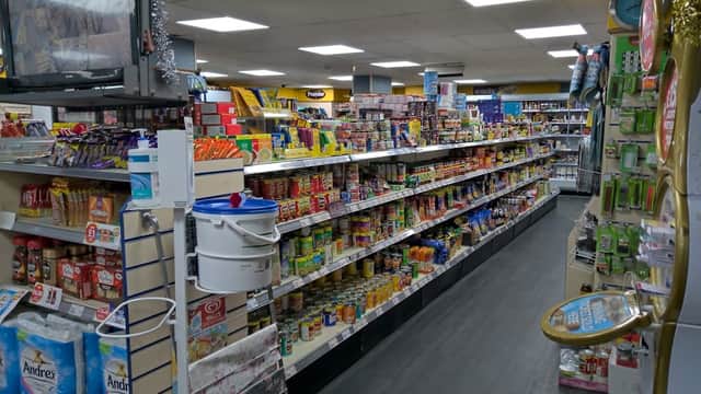 Aisles of shelves stocked with various groceries and snacks in a well-lit convenience store.