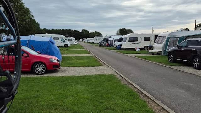 Campsite with caravans and tents lined along a grassy path under a cloudy sky in Kirby Misperton, Yorkshire.