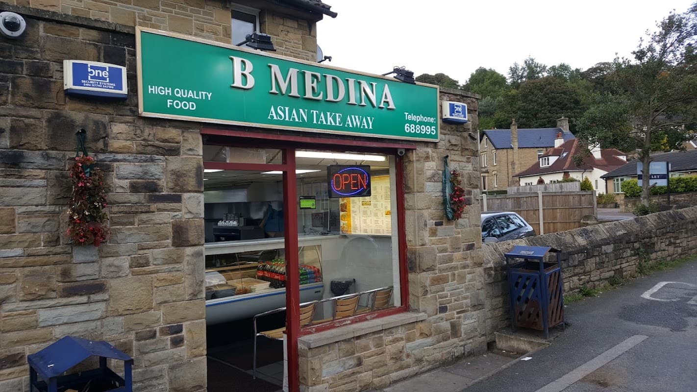 Green sign with "B Medina Asian Takeaway," stone building, open sign, takeaway window, nearby residential area.