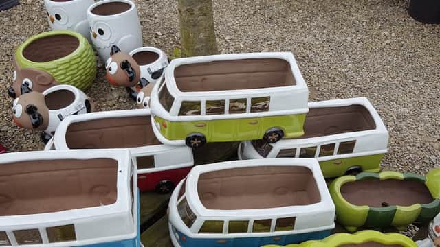 Colorful ceramic plant pots shaped like vintage vans and animals, displayed on gravel at The Green Frog Garden Shop.