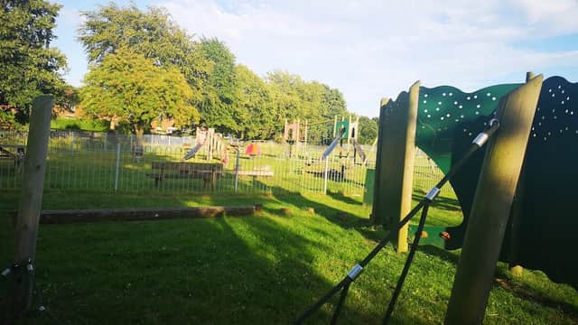 Playground in Hemingbrough with climbing frames, swings, and grassy areas under a blue sky with scattered clouds.