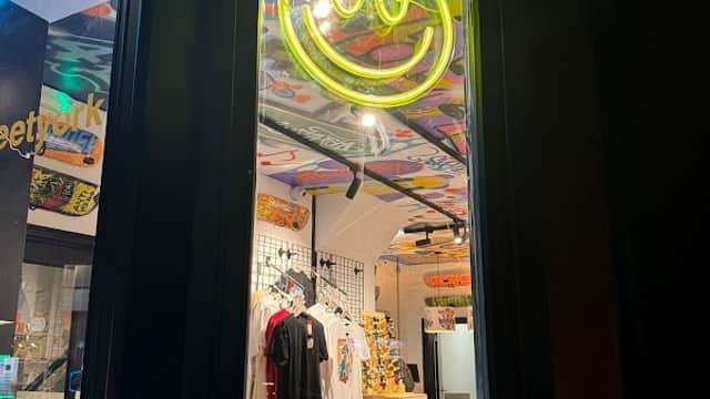 Neon smiley face sign illuminates the window of Easy Street sports shop, showcasing vibrant interior and merchandise.