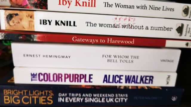 A stack of books including titles by Iby Knill, Ernest Hemingway, and Alice Walker, with colorful covers.