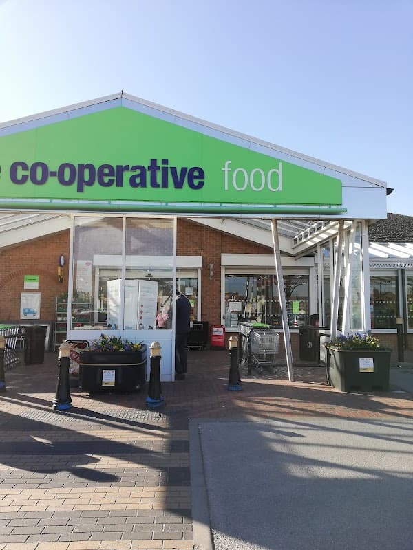 Co-op Food store entrance in Stocksbridge, Yorkshire, with outdoor seating and flower planters.