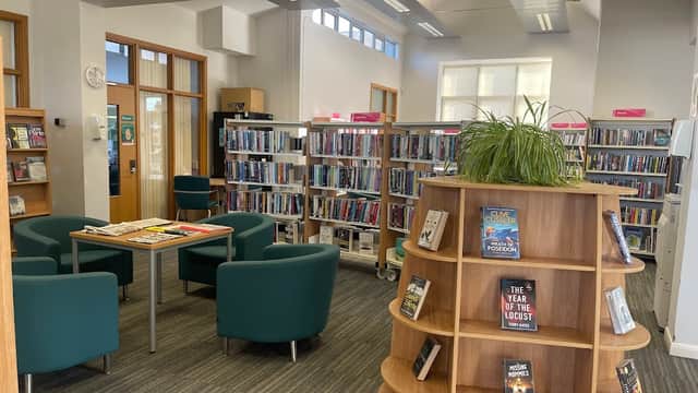 Bright interior of Driffield Library with bookshelves, seating area, and a wooden display stand for books.