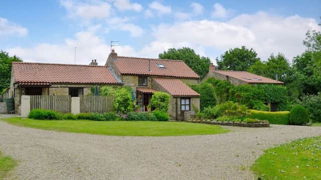 Charming stone cottages with red-tiled roofs, set in lush greenery and a gravel driveway in Sawdon, Yorkshire.