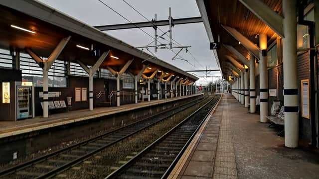 Platform view at Rotherham Central station, featuring overhead lines, waiting areas, and illuminated signage.