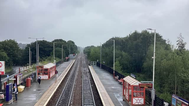 Bus stops with red shelters along a railway track, surrounded by trees under a cloudy sky in Pontefract, Yorkshire.