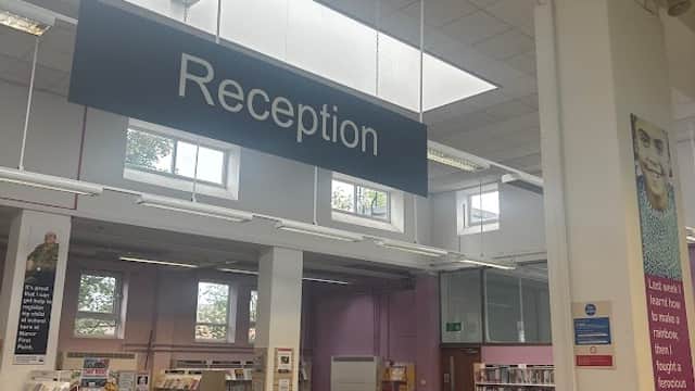 Reception area of Sheffield City Council First Point - Manor Library, featuring desks, computers, and bookshelves.
