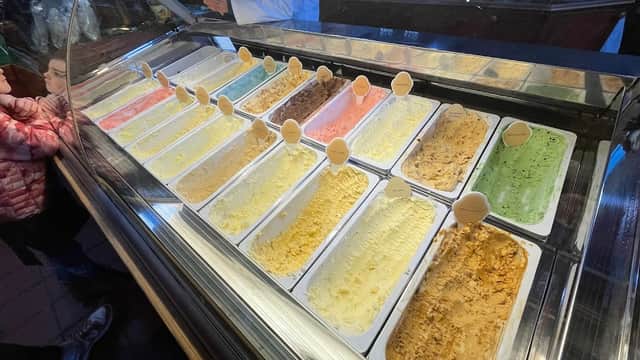 Colorful selection of gelato in a display case at Goodalls of Tong, with customers in the background.
