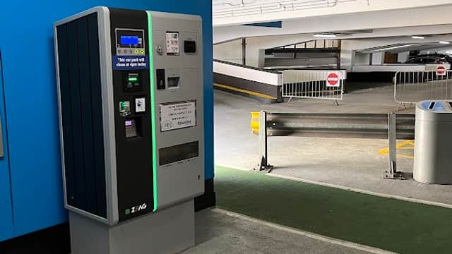 Pay & Display machine in a multi-storey car park, with barriers and an open parking area in the background.