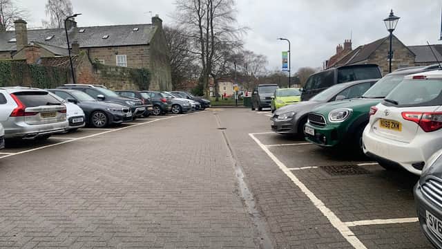 Car park with various parked vehicles, trees in the background, and a cloudy sky in Ayton, Yorkshire.