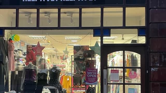 PDSA Charity Shop storefront with colorful signage, clothing displays, and a welcoming entrance.