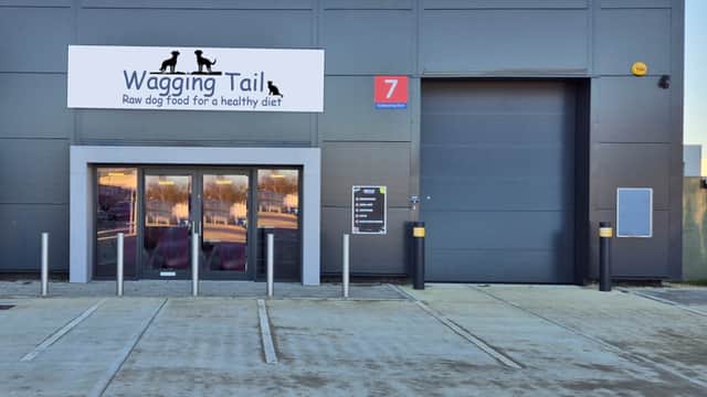 Entrance of Wagging Tail Raw Dog Food shop with a large sign, parking area, and a loading dock in York, Yorkshire.