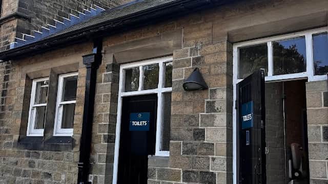 Free parking area with a stone building featuring two restroom doors labeled "TOILET'S."