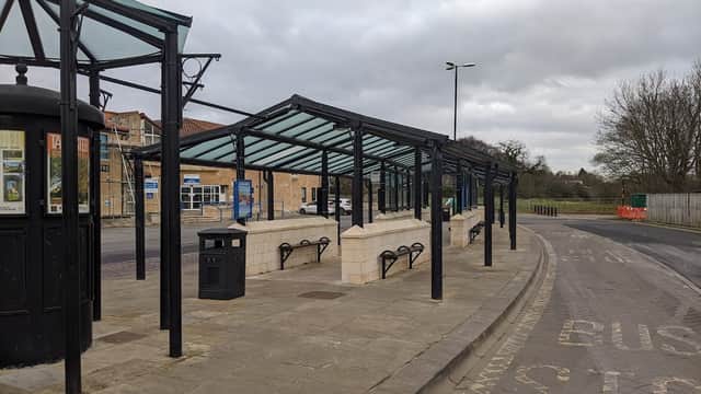 Tadcaster bus station features covered waiting areas, benches, and a trash bin along a quiet street.