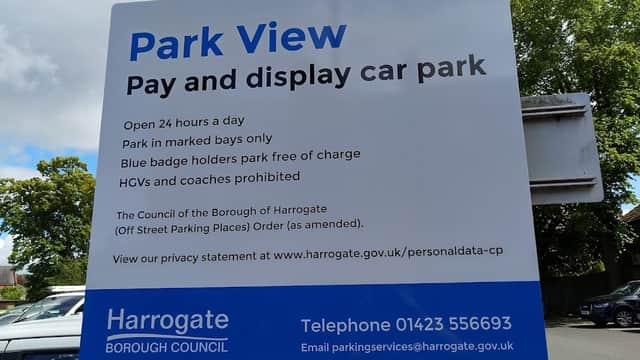 Sign for Park View car park in Harrogate, detailing parking rules and contact information. Trees in the background.