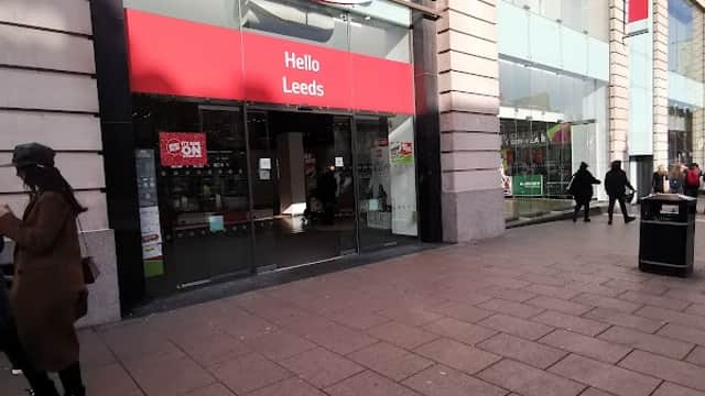 Argos store front in Leeds with a red sign, featuring "Hello Leeds" and shoppers walking by on the pavement.