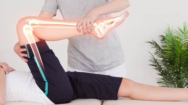 Physiotherapist assisting a patient with a knee treatment, showcasing joint movement and anatomical overlay.