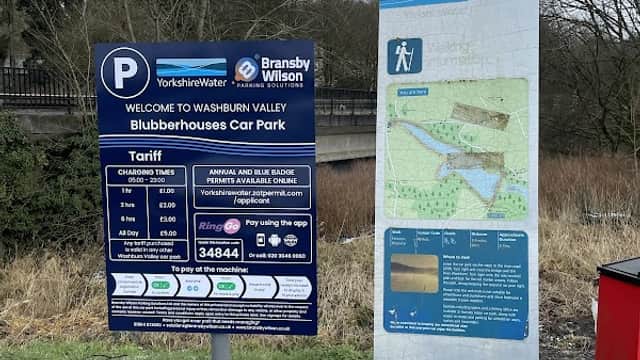 Blubberhouses Car Park sign with parking information and tariff details, surrounded by grass and trees in Yorkshire.
