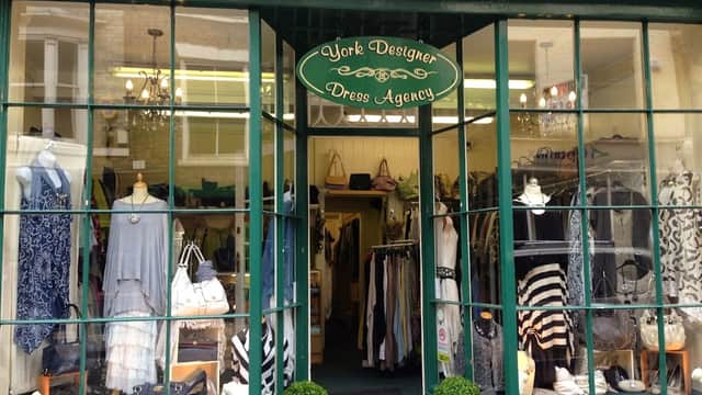 Storefront of York Designer Dress Agency with clothing displays, mannequins, and potted plants at the entrance.