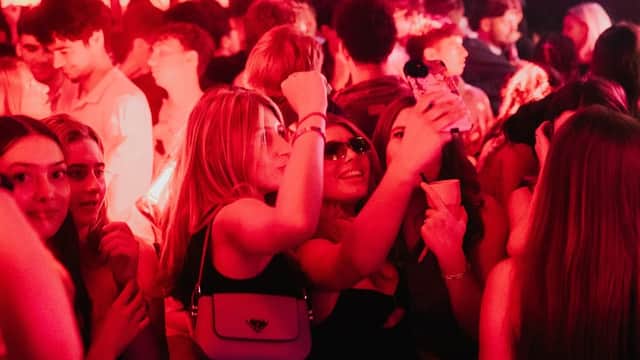 Crowd of young people enjoying themselves at CIRCUIT York nightclub, vibrant red lighting, taking selfies and dancing.