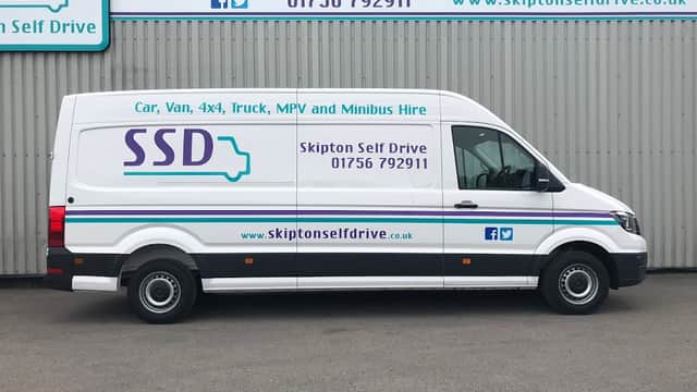 White van with "Skipton Self Drive" branding, contact details, and website, parked against a gray building.