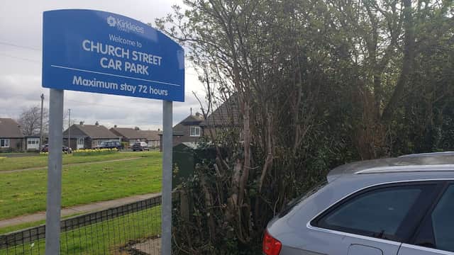 Sign for Church Street Car Park in Clayton West, with a silver car parked nearby and houses visible in the background.