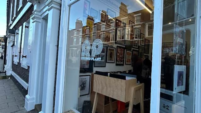 Storefront of Record Plant York featuring a display window with framed pictures and a wooden display stand.