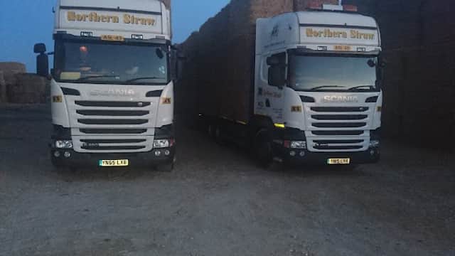 Two Scania trucks loaded with bales of straw parked in a gravel area at Northern Straw Co Ltd, Great Heck, Yorkshire.