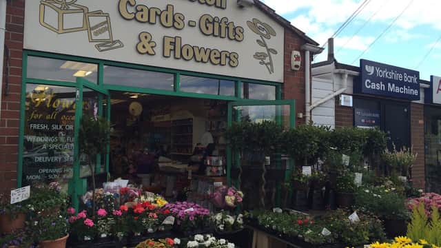Brightly colored flowers and plants outside a shop with a sign reading "Whiston Cards Gifts & Flowers" in Canklow, Yorkshire.