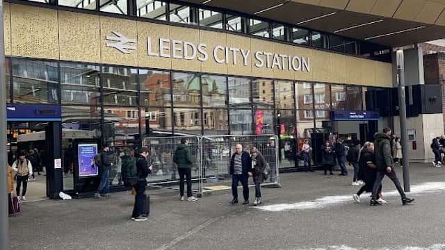 Leeds City Station entrance with people, modern architecture, and signage, set against a cloudy sky.