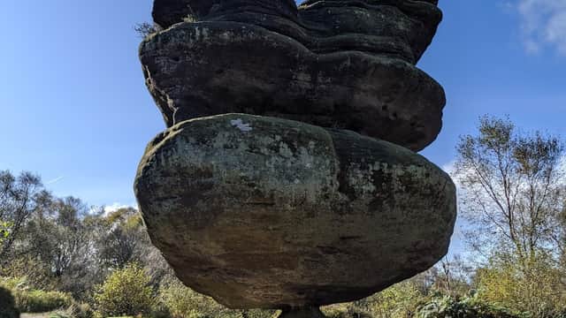 Unique balancing rock formation surrounded by greenery and blue sky at Brimham Rocks, Summerbridge, Yorkshire.